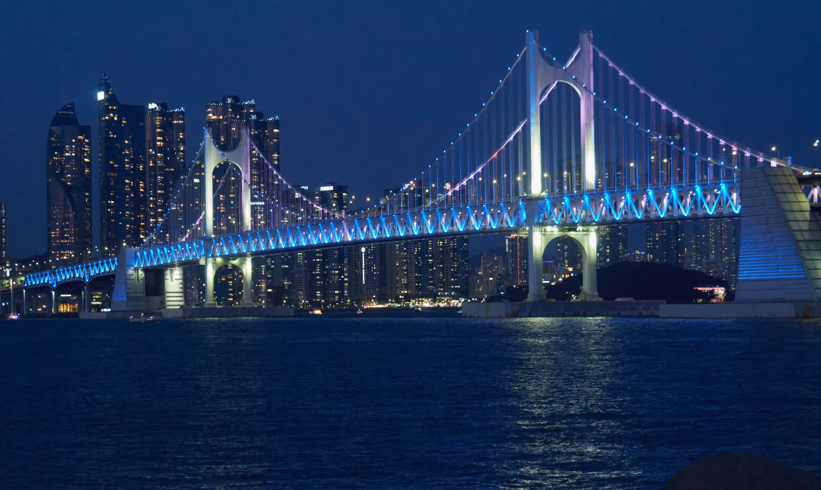 Blue and violet lights on Gwangan Bridge above the sea, viewed from Gwangalli Beach
